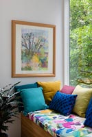 Peinture encadrée sur le siège de la fenêtre avec des coussins colorés