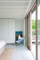 Chaise papillon pliante dans une chambre contemporaine minimale avec portes coulissantes