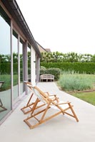 Chaises longues sur terrasse pavée de maison contemporaine