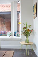 Grande assise de fenêtre et table d'appoint avec des fleurs dans un vase