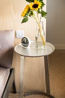 Petite table de chevet circulaire et vase de tournesols