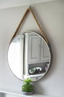 Miroir circulaire suspendu par une corde
