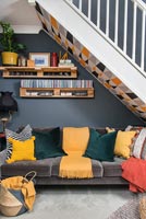 Canapé sous escalier dans un salon ouvert moderne et coloré