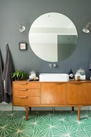 Buffet vintage avec lavabo dans salle de bain moderne avec sol vert clair
