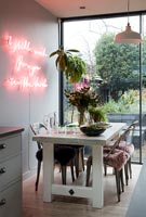 Oeuvre au néon rose lumineux sur le mur caractéristique de la salle à manger contemporaine