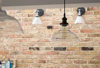 Lampes suspendues et murales sur mur de briques apparentes