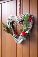 Couronne de Noël en forme de coeur sur porte en bois