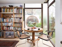 Table circulaire avec chaises en étude avec étagères et grandes fenêtres