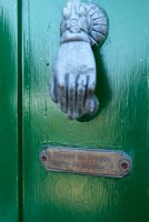 Heurtoir de porte en forme de main et plaque sur la porte d'entrée peinte en vert