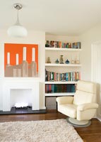 Salon moderne avec chaise en cuir et œuvres d'art au-dessus de la cheminée