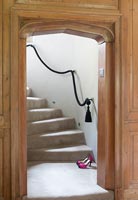 Vue à travers l'arc de porte en bois à l'escalier avec détail de corde
