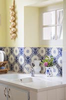 Carreaux décoratifs bleu et blanc derrière un double évier dans la cuisine