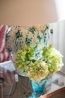 Fleurs coupées vert lime dans un vase par lampe sur une table d'appoint