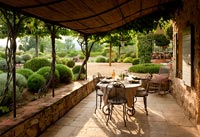 Terrasse couverte avec table à manger donnant sur les jardins à la française