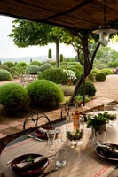 Table à manger extérieure sur terrasse couverte donnant sur les jardins à la française