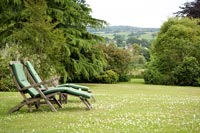 Chaises longues sur une grande pelouse avec vue sur la campagne au-delà