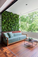 Canapé sur le balcon en bois espace de vie extérieur et mur végétal vert