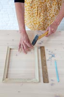 Accessoires d'artisanat sur table - femme martelant un clou dans un cadre en bois