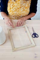 Accessoires d'artisanat sur table - femme attachant du fil au cadre photo en bois