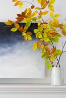 Branches remplies de feuilles d'automne dans un vase sur la cheminée