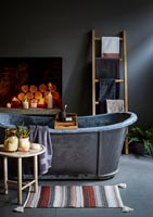 Baignoire autoportante en métal dans une salle de bain gris foncé avec sol en béton