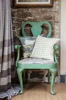 Chaise en bois peint vert menthe contre mur de pierre