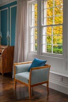 Chaise antique à rayures par fenêtre dans la chambre classique
