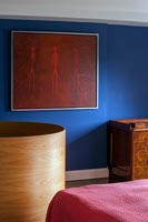 Oeuvre moderne rouge sur mur peint bleu dans la chambre