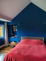 Chambre avec couvre-lit rouge et murs peints en bleu