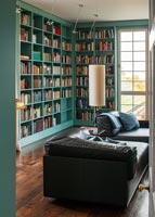 Canapé en cuir noir dans la bibliothèque avec étagères peintes turquoise