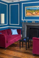 Murs peints en bleu azur et canapés en velours rose dans le salon classique