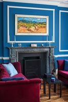 Murs peints bleu azur et blanc et canapés en velours rose dans le salon classique