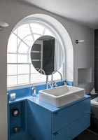 Salle de bain bleu et blanc avec fenêtre cintrée