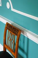 Chaise ancienne à côté d'un mur peint en bleu avec moulures originales