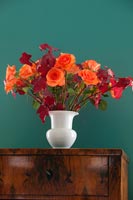 Vase de roses orange avec des feuilles d'érable d'automne