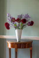 Fleurs rouges et violettes dans un vase blanc sur une table console antique