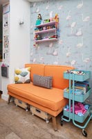 Papier peint flamant rose et canapé orange dans la chambre d'enfant colorée