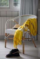 Plaid jaune sur chaise en osier blanc