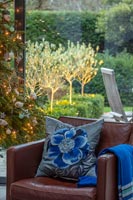 Coussin floral bleu brodé sur fauteuil en cuir à côté de l'arbre de Noël.