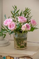 Roses roses dans un vase sur la table de chevet
