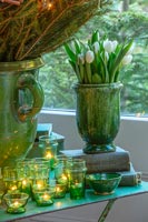 Vase en céramique de tulipes blanches sur table avec des bougies de Noël