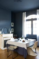 Salle à manger bleu foncé avec un mobilier blanc
