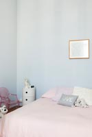 Murs bleu pâle et literie rose dans la chambre des enfants