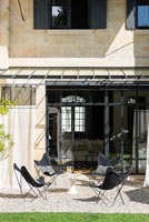 Salon de jardin sur terrasse en gravier avec rideaux pour l'ombre