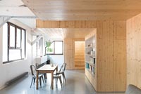 Salle à manger contemporaine avec murs en bois et sol en béton ciré