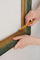 Utilisation d'un crayon pour marquer la forme du cadre photo sur le mur
