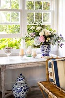 Table vintage avec arrangement de fleurs dans un vase en céramique bleu et blanc