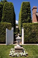 Lanterne en pierre dans un jardin à la française avec porte en bois blanc