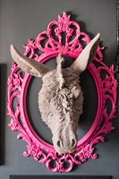 Sculpture tête d'âne dans un cadre rose sur mur noir
