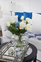 Roses blanches dans un vase en verre sur un plateau en argent